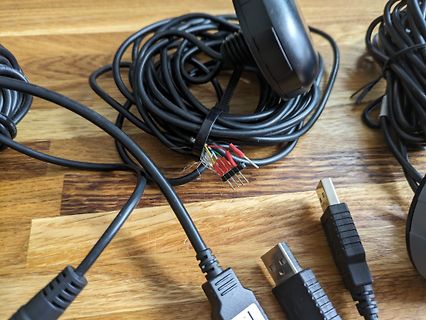 Diverse Kabel, Stecker und ein aufgewickeltes Kabel auf Holz
