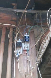 Unordentliche Verkabelung an zwei Schaltern an einem Holzpfosten