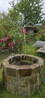 Steinbrunnen mit Wasserfontäne im Garten