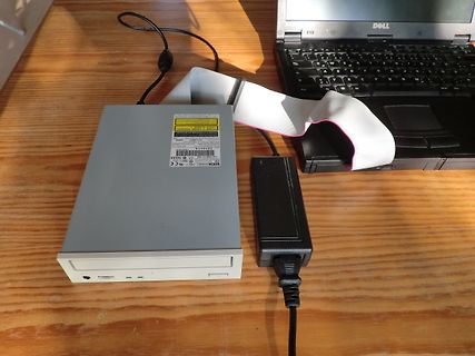 Externes CD-Laufwerk und Laptop auf Holztisch