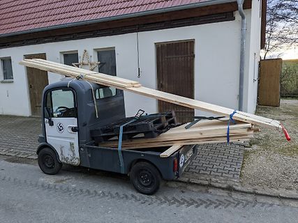 Kleiner Lastwagen mit Holzlatten auf einer Straße
