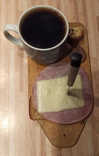 Kaffee und belegtes Brot auf Holzbrett