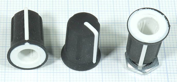 Drei schwarze Kunststoff-Drehknöpfe auf Millimeterpapier