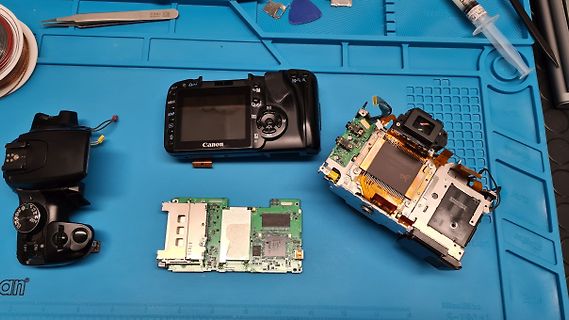 Zerlegte Canon Kamera auf blauer Werkstattmatte