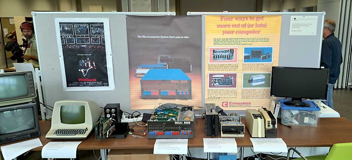 Retro-Computer und Poster auf einem Messestand
