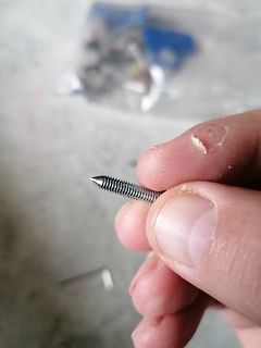 Hand hält eine kleine Schraube