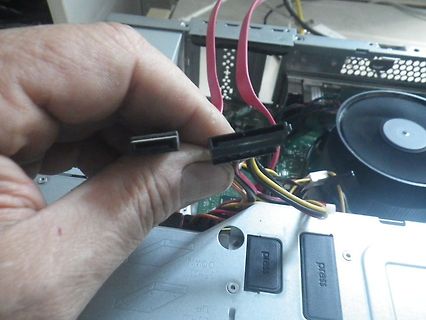 Hand hält SATA-Strom- und Datenkabel vor PC-Gehäuse