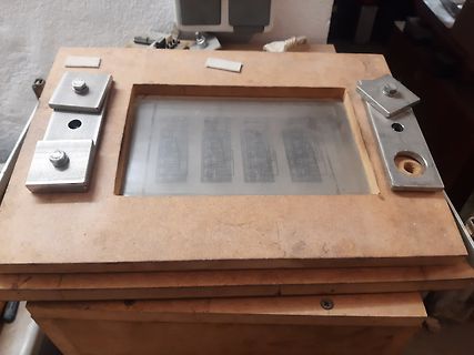 Fotografie einer Glasplatte auf einem Holzrahmen mit Metallklemmen