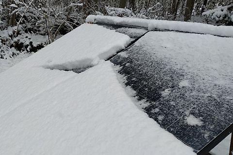 Schneebedeckte Solarmodule im Wald