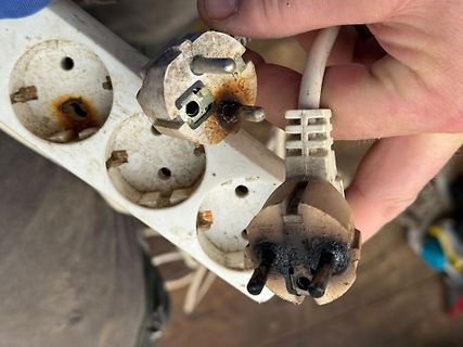 Beschädigter Stecker und Steckdose mit Brandspuren