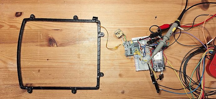 Elektronik-Aufbau mit Breadboard, Mikrocontroller und Rahmen auf Holzuntergrund