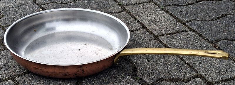 Kupferpfanne mit Messingstiel auf Pflastersteinen