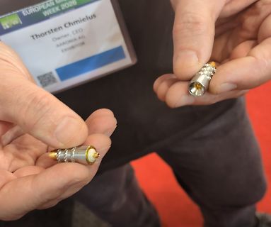 Person hält zwei kleine metallische Bauteile