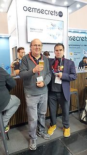 Zwei Männer vor einem oemsecrets.com Stand