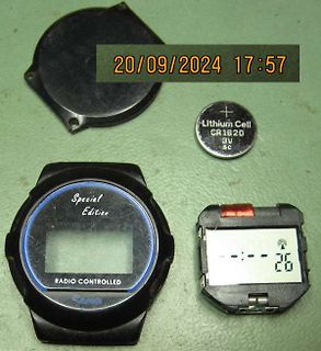Zerlegter Digitaluhr-Mechanismus mit Batterie und Gehäuseteilen