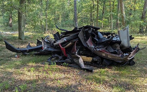 Trümmerhaufen von Autoteilen im Wald