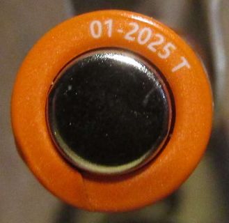 Nahaufnahme eines orangefarbenen Bauteils mit Datumsstempel