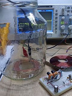 Elektronischer Aufbau mit Glasgefäß, Spule und Breadboard
