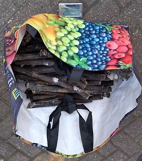 Gefüllter Sack mit Holzscheiten und digitaler Waage