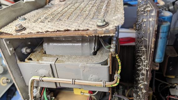 Innenansicht eines defekten Netzteils mit verschmutzten Bauteilen