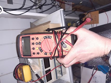 Hand hält Multimeter in Werkstatt