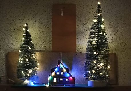 Beleuchtete Weihnachtsdekoration mit Tannenbäumen und Haus
