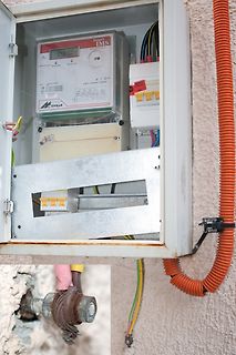 Geöffneter Stromzähler und Sicherungskasten an Wand