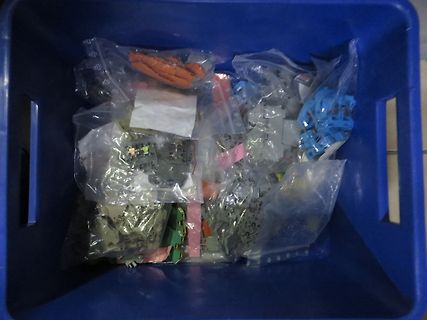 Plastikteile in Beuteln in einer blauen Kiste