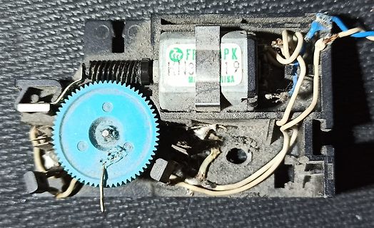 Innenansicht eines defekten elektrischen Bauteils mit Zahnrad