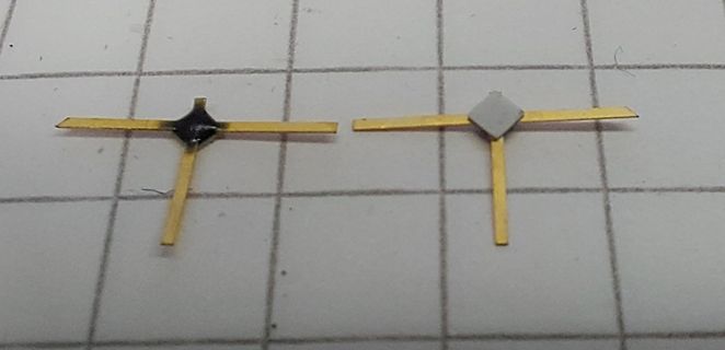 Zwei kleine goldene Bauteile auf Millimeterpapier