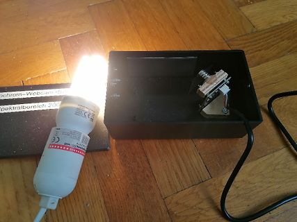 Leuchtmittel und Elektronikbauteil in Gehäuse auf Holzboden