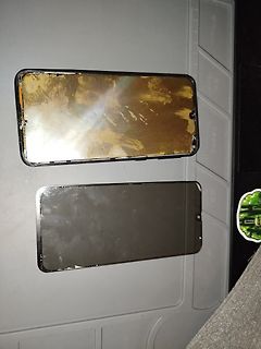 Zwei beschädigte Smartphone-Displays auf einer Unterlage