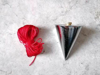 Rotes Kabel und silberner Kegel auf hellem Untergrund