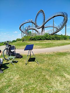 Solarpanel und Fahrrad vor einer Skulptur