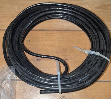 Aufgewickeltes schwarzes Kabel auf Holzuntergrund