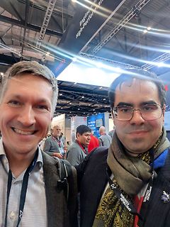 Zwei lächelnde Männer auf einer Messe