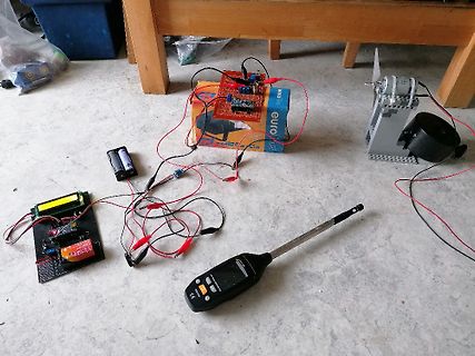 Elektronik-Versuchsaufbau mit Leiterplatten, Batterien und Multimeter