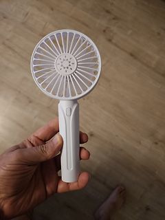 Hand hält einen weißen Handventilator