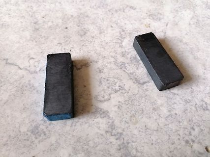 Zwei schwarze Magnetblöcke auf Marmoroberfläche