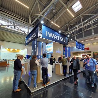 Menschen an einem Messgeräte-Stand auf einer Messe