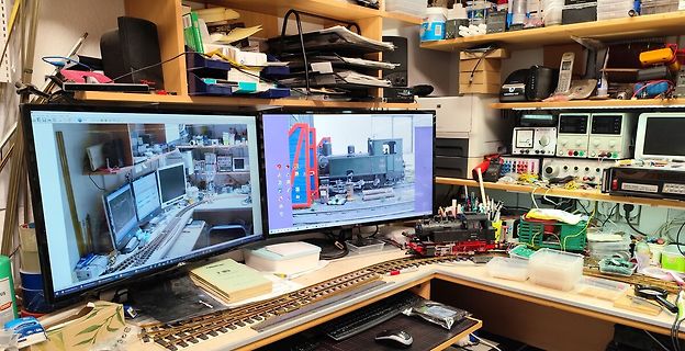 Arbeitsplatz mit zwei Monitoren und Modellbahnanlage