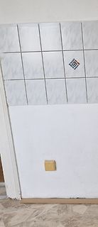 Weiße Fliesenwand und weiße Wand mit Steckdose