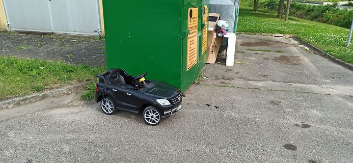 Spielzeugauto vor Müllcontainer