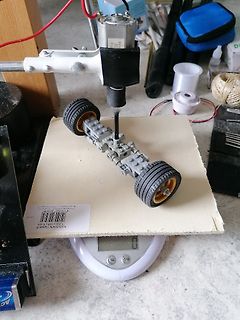 Modellauto auf einer Waage unter einem Bohrer