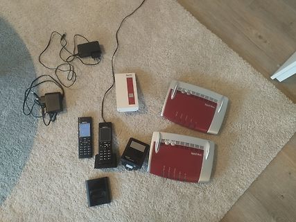 Verschiedene Router, Netzteile und ein Telefon auf Teppich