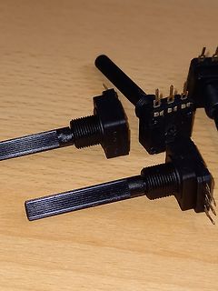 Drei schwarze Potentiometer auf Holzuntergrund