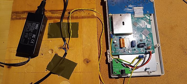 Geöffnetes elektronisches Gerät mit Netzteil auf Holzbrett