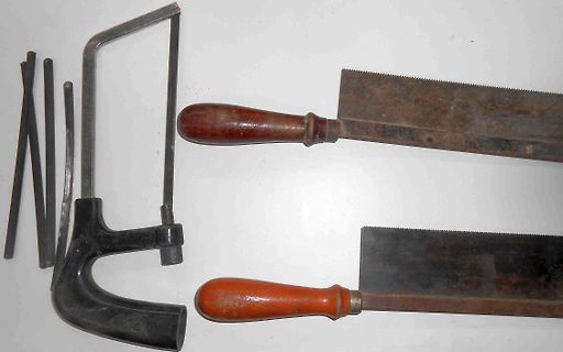 Sägen und Metallstifte auf weißem Grund