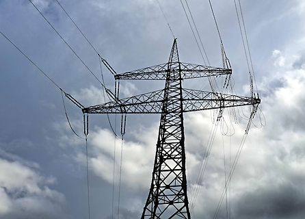 Hochspannungsmast vor bewölktem Himmel