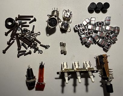 Diverse Elektronikbauteile und Schrauben auf weißem Untergrund